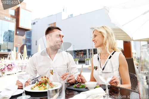 Image of happy couple eating dinner at restaurant terrace