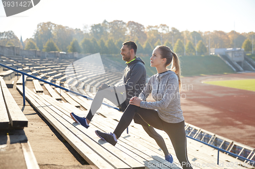 Image of couple stretching leg on stands of stadium