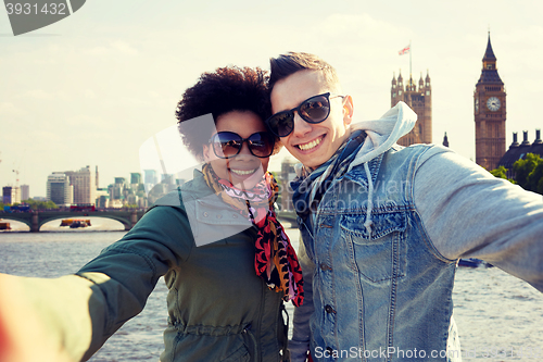 Image of happy teenage couple taking selfie in london city