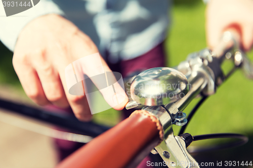 Image of close up of male hand ringing bell on bike wheel