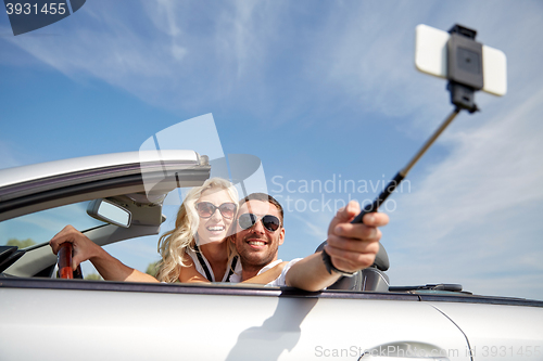 Image of happy couple in car taking selfie with smartphone