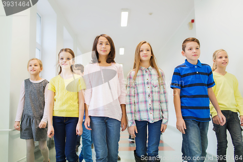 Image of group of smiling school kids walking in corridor