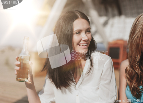 Image of girl with drink and friends on the beach