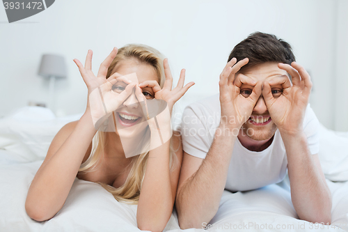 Image of happy couple lying in bed at home