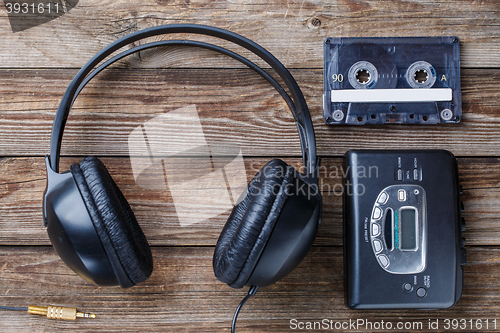 Image of Headphones, player and retro compact cassette over wooden background. Top view