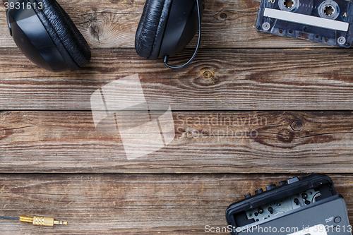 Image of Cassette tapes, cassette player and headphones over wooden table. top view.