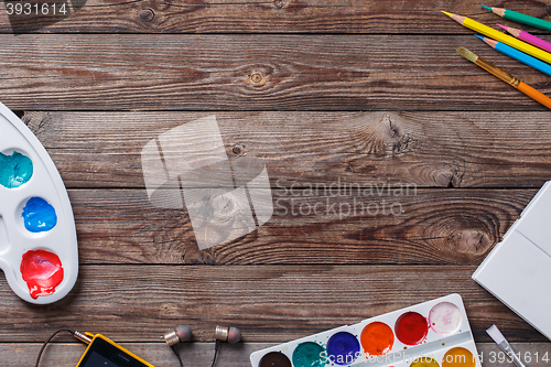 Image of Paper, watercolors, paint brush and some art stuff on wooden   table