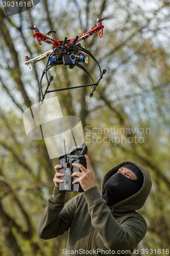 Image of Man in mask operating a drone with remote control.