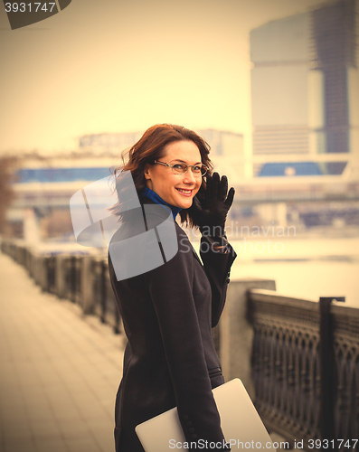 Image of friendly brunette with a computer outdoors