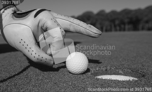 Image of man\'s hand putting golf ball in hole