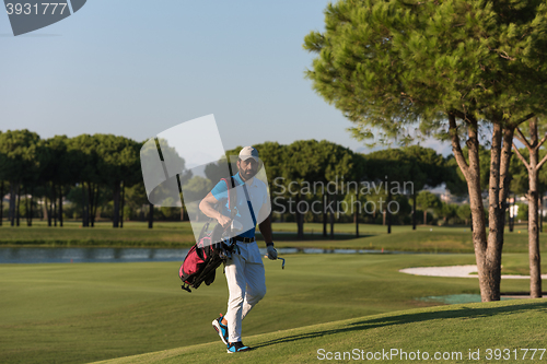 Image of golfer  walking and carrying bag