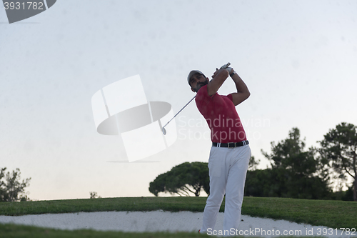 Image of golfer hitting a sand bunker shot on sunset