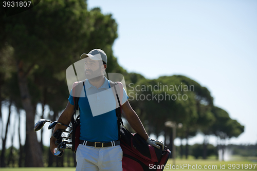 Image of golf player walking and carrying bag