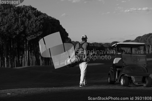 Image of golfer  walking and carrying golf  bag