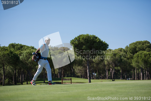 Image of golf player walking and carrying bag