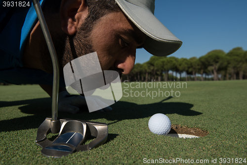 Image of golf player blowing ball in hole