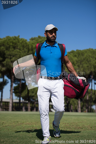 Image of golf player walking and carrying bag