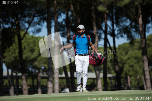 Image of golf player walking and carrying bag