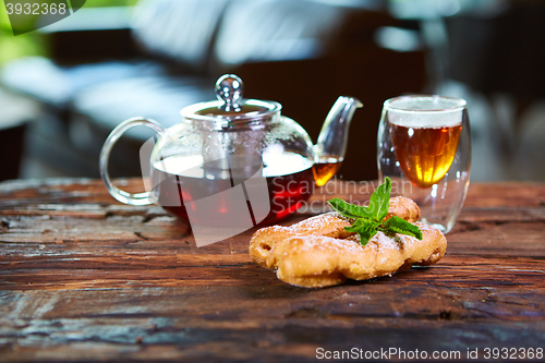 Image of Tasty eclair and cup of tea on wooden table