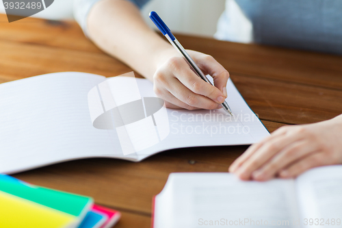 Image of close up of student with book and notebook at home