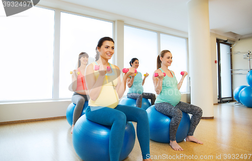 Image of happy pregnant women exercising on fitball in gym