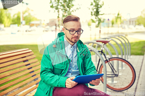 Image of happy young hipster man with tablet pc and bike