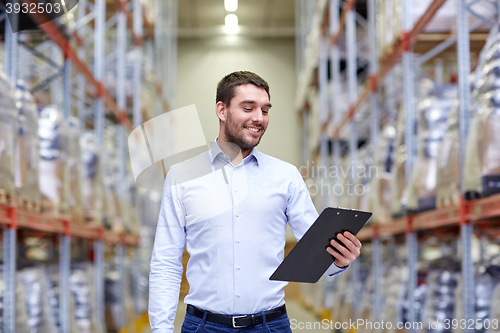 Image of happy businessman with clipboard at warehouse