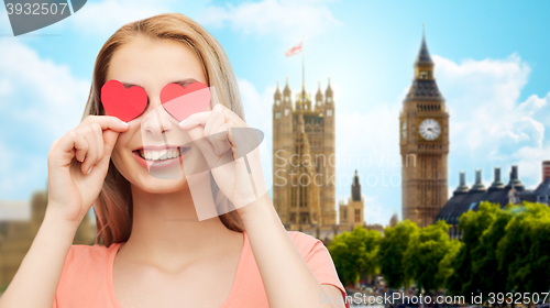 Image of happy young woman with red heart shapes on eyes