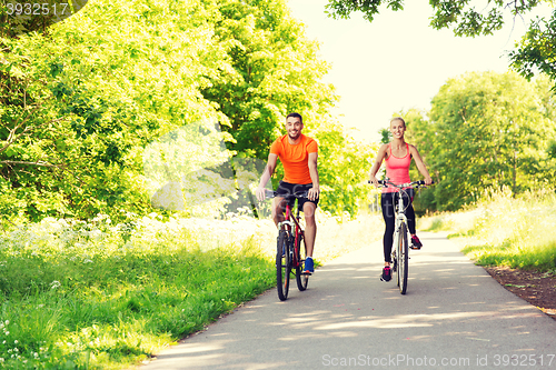 Image of happy couple riding bicycle outdoors