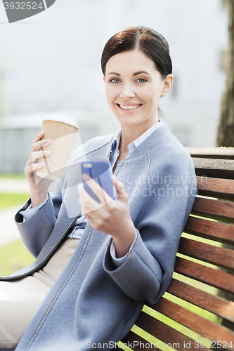 Image of smiling woman with coffee and smartphone