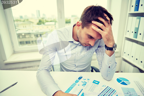 Image of stressed businessman with papers in office