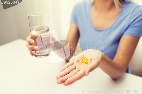 Image of close up of woman hands with capsules and water