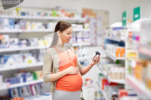 Image of happy pregnant woman with medication at pharmacy