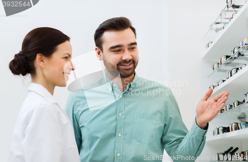 Image of optician and man choosing glasses at optics store