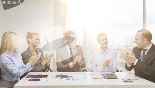 Image of business team with laptop clapping hands