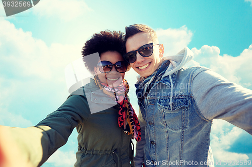 Image of happy teenage couple taking selfie over blue sky