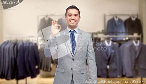 Image of happy businessman in suit over clothing store