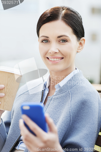 Image of smiling woman with coffee and smartphone