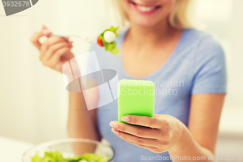 Image of close up of woman with smartphone eating salad