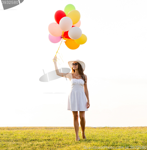 Image of smiling young woman in sunglasses with balloons