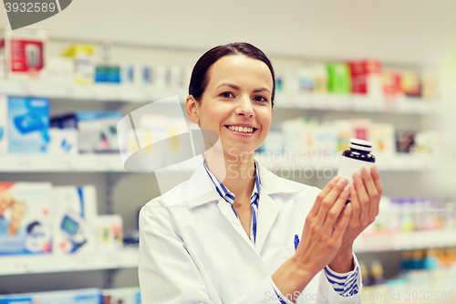 Image of happy female pharmacist with drug jar at pharmacy