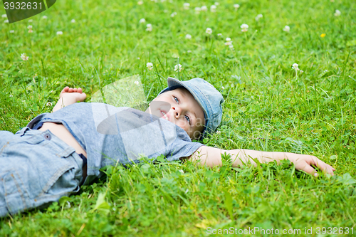 Image of Little caucasian boy resting on grass