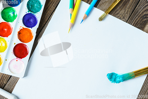 Image of Art tools. Watercolor Paints and brushes with blank white paper  on wooden background close up.