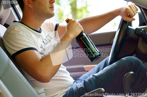 Image of Man drinking beer while driving the car.