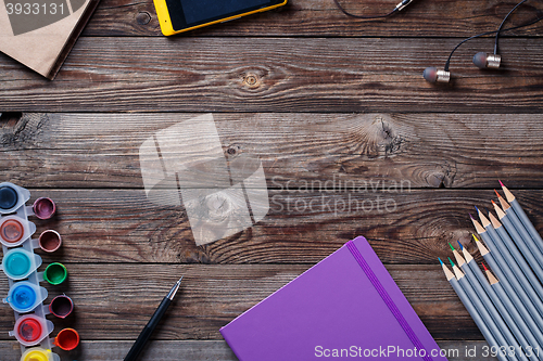 Image of Watercolors, color pencils and sketchbook on wooden table. Flat lay photo with empty space for logo, text.