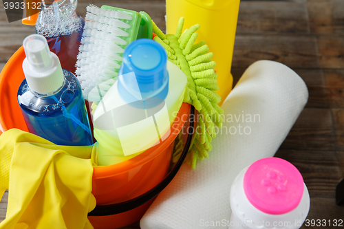 Image of Plastic bucket with cleaning supplies on wood background