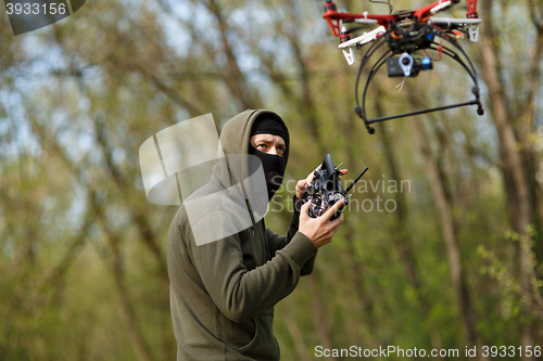 Image of Man in mask operating a drone with remote control.