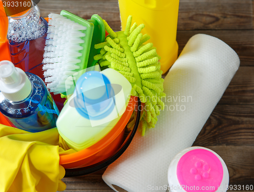 Image of Plastic bucket with cleaning supplies on wood background