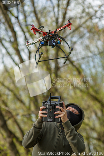 Image of Man in mask operating a drone with remote control.