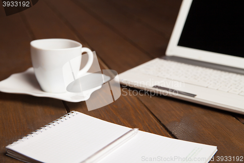 Image of Cup of coffee,notebook and laptop on table